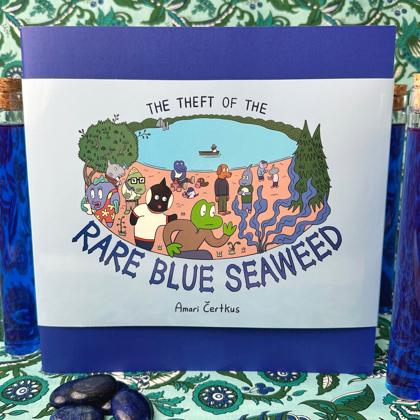 The Theft of the Rare Blue Seaweed print comics with decorative vials and pebbles